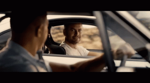 A Man In A White Shirt Is Looking Out The Window Of Another Man 'S Car GIF