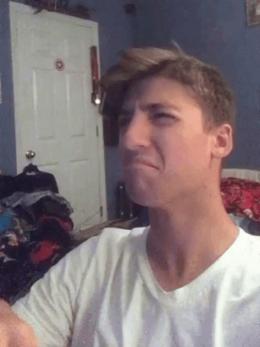a man in a white shirt is making a funny face in front of a door
