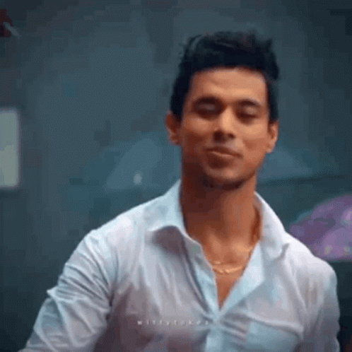 A Man In A White Shirt Is Making A Funny Face While Standing In A Room . GIF