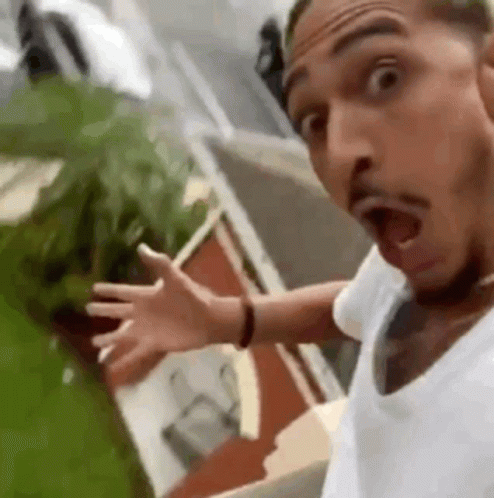 A Man In A White Shirt Is Making A Funny Face With His Mouth Open And His Arms Outstretched . GIF