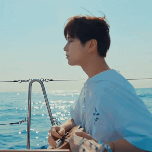 A Man In A White Shirt Is Playing A Guitar In The Ocean GIF