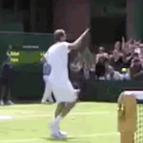 a man in a white shirt is playing tennis on a green court