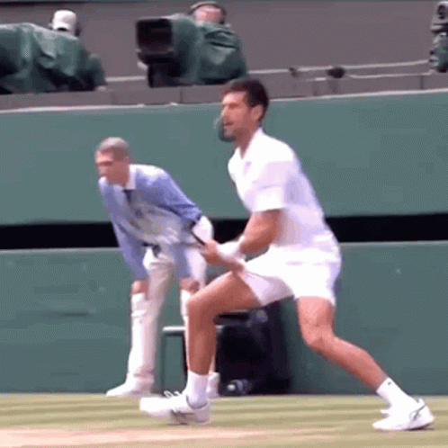 A Man In A White Shirt Is Playing Tennis On A Tennis Court GIF