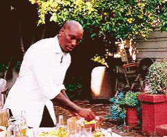 A Man In A White Shirt Is Preparing A Meal Outside GIF