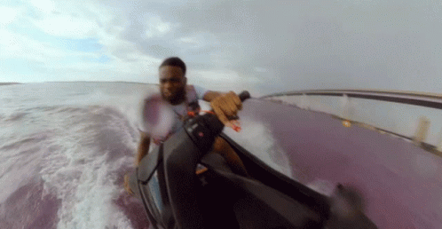A Man In A White Shirt Is Riding A Jet Ski GIF