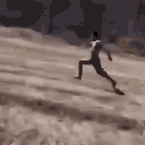 A Man In A White Shirt Is Running On A Sandy Hill GIF