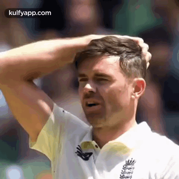 A Man In A White Shirt Is Scratching His Head With His Hands . GIF