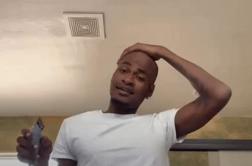 A Man In A White Shirt Is Shaving His Head With A Trimmer . GIF
