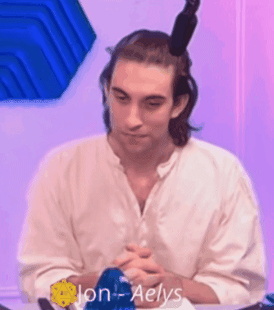 A Man In A White Shirt Is Sitting At A Table With His Hands Folded . GIF