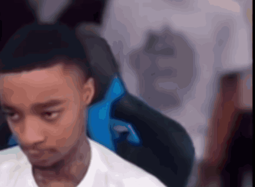 A Man In A White Shirt Is Sitting In A Blue Chair With His Eyes Closed GIF