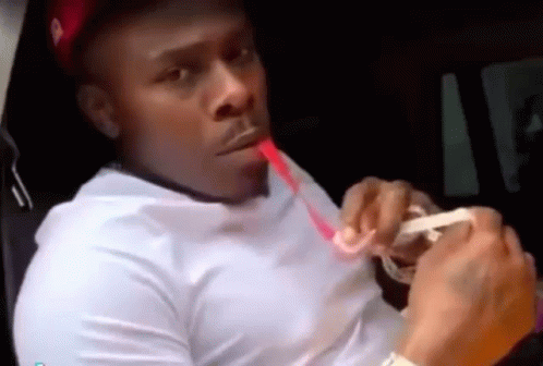 A Man In A White Shirt Is Sitting In A Car Drinking From A Straw . GIF
