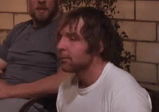 A Man In A White Shirt Is Sitting In A Chair Next To Another Man In A Gray Shirt . GIF