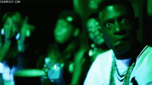 A Man In A White Shirt Is Sitting In A Dark Room With A Green Light Behind Him And The Words Senorgif.com Visible GIF