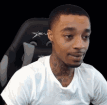 A Man In A White Shirt Is Sitting In A Gaming Chair And Making A Funny Face . GIF