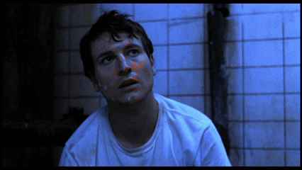 Man In White Shirt Sitting In Front Of Blue Tiles GIF