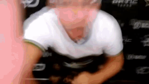 A Man In A White Shirt Is Sitting In Front Of A Sign That Says League . GIF