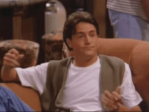 A Man In A White Shirt Is Sitting On A Couch With His Arms Outstretched GIF