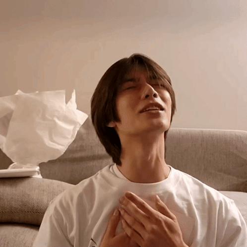A Man In A White Shirt Is Sitting On A Couch With His Eyes Closed GIF