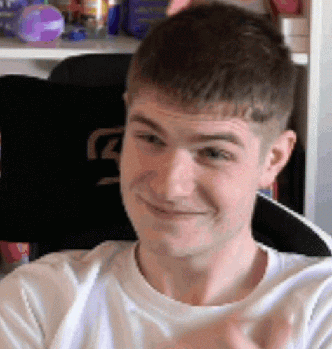a man in a white shirt is smiling and clapping his hands .