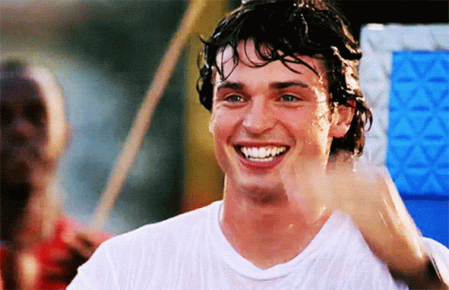 A Man In A White Shirt Is Smiling And Waving At Someone GIF