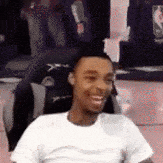 A Man In A White Shirt Is Smiling In Front Of A Mirror GIF