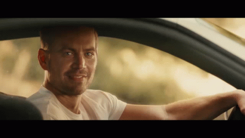 A Man In A White Shirt Is Smiling While Sitting In A Car GIF