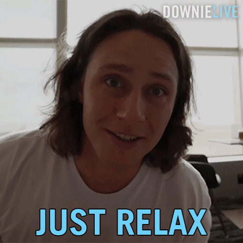 A Man In A White Shirt Is Smiling With The Words Just Relax Below Him GIF