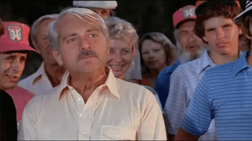 A Man In A White Shirt Is Standing In A Crowd Of People Wearing Hats With The Letter X On Them GIF