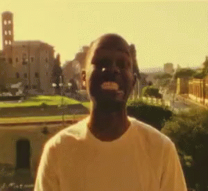 A Man In A White Shirt Is Standing In Front Of A Castle GIF