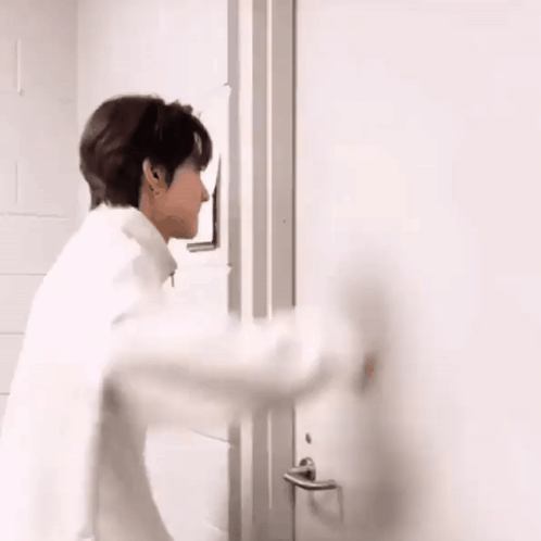 a man in a white shirt is standing in front of a door .