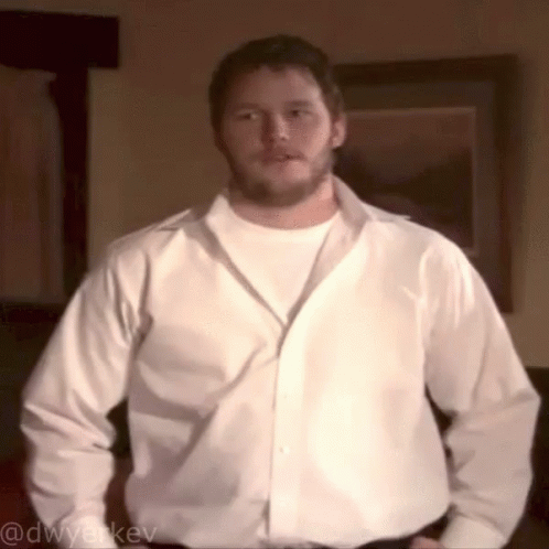 A Man In A White Shirt Is Standing In Front Of A Framed Picture And Has The Username @Dwyerkev On The Bottom GIF