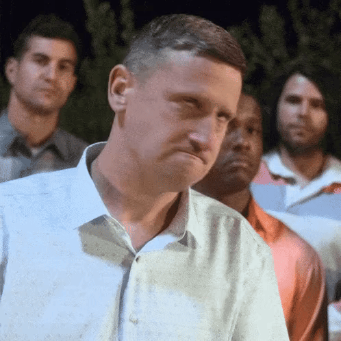 A Man In A White Shirt Is Standing In Front Of A Group Of Men GIF