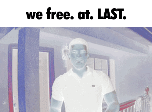 A Man In A White Shirt Is Standing In Front Of A House With The Words " We Free At Last " Above Him GIF