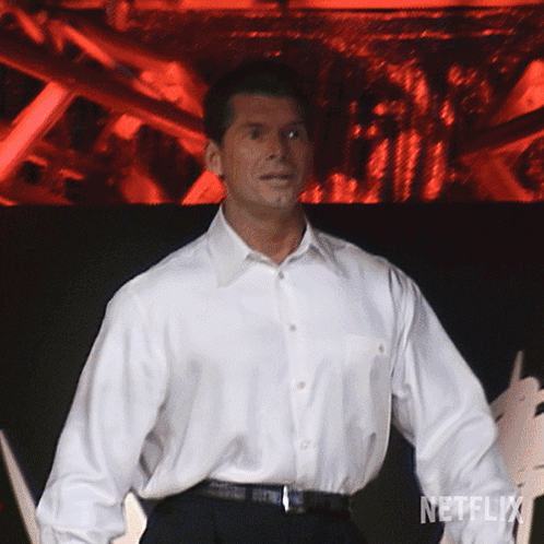 A Man In A White Shirt Is Standing In Front Of A Netflix Sign GIF
