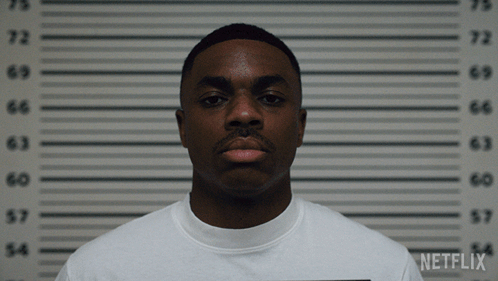 A Man In A White Shirt Is Standing In Front Of A Netflix Wall GIF