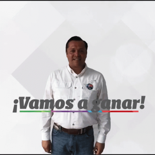 A Man In A White Shirt Is Standing In Front Of A Sign That Says " Vamos A Ganar " GIF