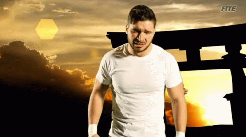 A Man In A White Shirt Is Standing In Front Of A Sunset With The Word Fite On The Bottom Left GIF