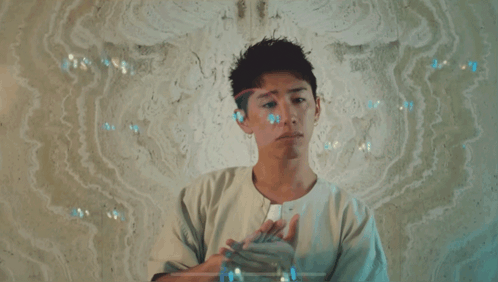 A Man In A White Shirt Is Standing In Front Of A Wall With Bubbles Coming Out Of It GIF
