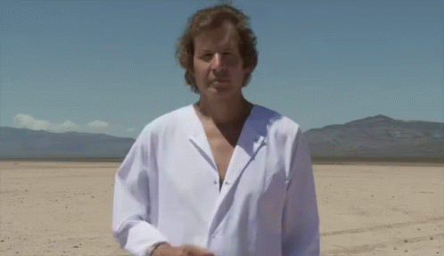 A Man In A White Shirt Is Standing In The Desert GIF
