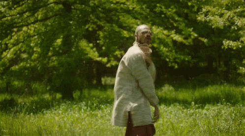 A Man In A White Shirt Is Standing In The Grass GIF
