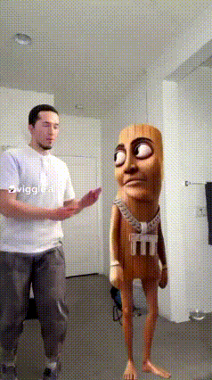 A Man In A White Shirt Is Standing Next To A Cartoon Character With A Shirt That Says M And M On It GIF
