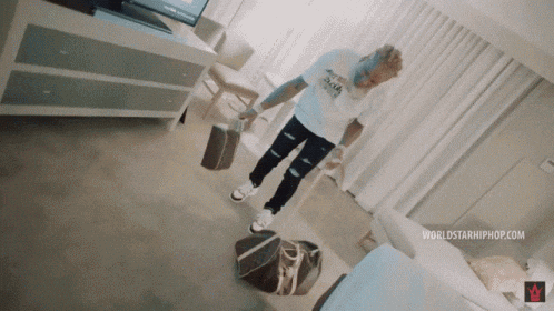 a man in a white shirt is standing on a bag in a room