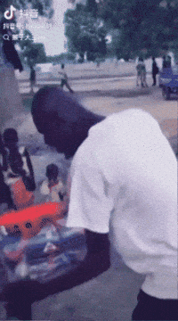 a man in a white shirt is standing on a street with a tiktok logo on the bottom left