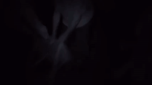 A Man In A White Shirt Is Standing On A Suitcase In A Room GIF