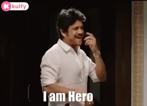 A Man In A White Shirt Is Talking On A Cell Phone While Standing In A Room . GIF