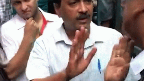 A Man In A White Shirt Is Talking To Another Man In A Crowd With His Hands Outstretched . GIF
