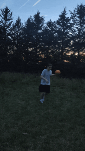A Man In A White Shirt Is Throwing A Frisbee In A Field With Trees In The Background GIF
