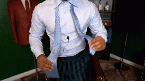 A Man In A White Shirt Is Tying A Tie GIF