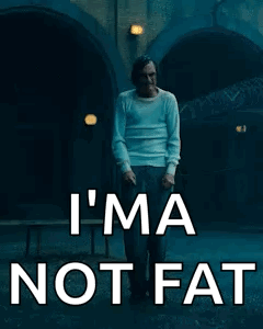 A Man In A White Shirt Is Walking Down A Street With The Words `` I 'M Not Fat '' Written On It . GIF