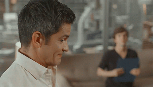 A Man In A White Shirt Looks At Another Man GIF